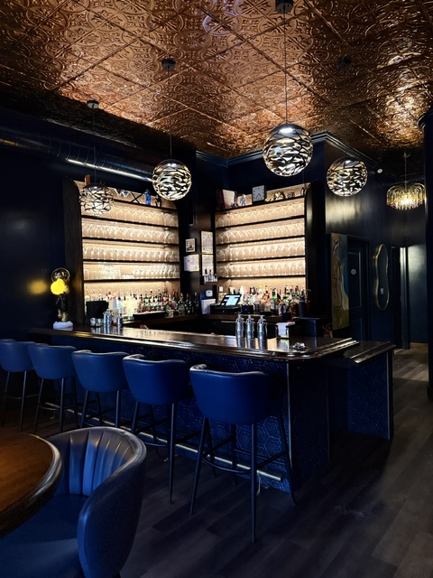 Backlit glassware shelves and pendant globes behind the bar